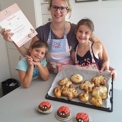 Mutter bäckt mit Kindern Cup Cakes und Ölgebäck bei Con Festi in Völs